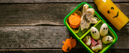 Halloween style school lunch box - ghost sandwich, pumpkin carrots, bananas, juiceの写真素材