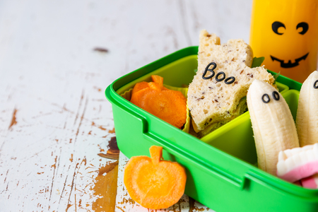 Halloween style school lunch box - ghost sandwich, pumpkin carrots, bananas, juiceの写真素材