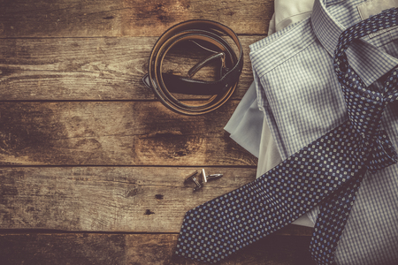 Selection of male clothes - stack of folded shirts, tie, belt, cufflinksの写真素材