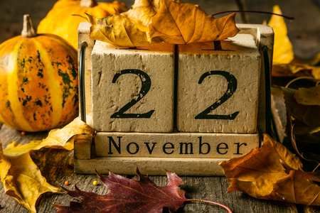 Thanksgiving concept - wood calendar with yellow leaves and pumpkinsの写真素材
