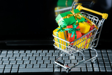 Ciber monday concept - trolley cart with christmas presents on notebookの写真素材