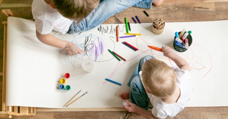 Kids painting with different materials on large canva on the flourの写真素材