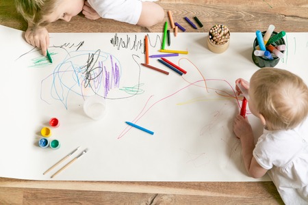 Kids painting with different materials on large canva on the flourの写真素材