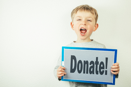 Donation concept - boy holding board with Donate on itの写真素材