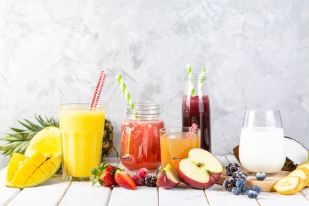 Selection of colourful smoothies in glasses with ingredientsの写真素材
