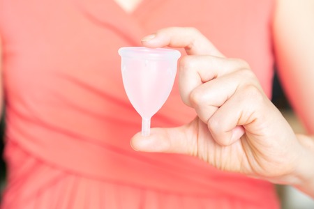 Zero waste concept - female holding menstrual cup in pink dressの写真素材
