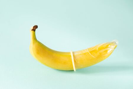 Sex education concept - banana in condom on pastel backgroundの写真素材