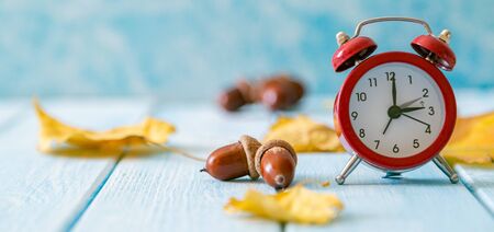 Autumn time change concept - red alarm clock on wood backgroundの写真素材
