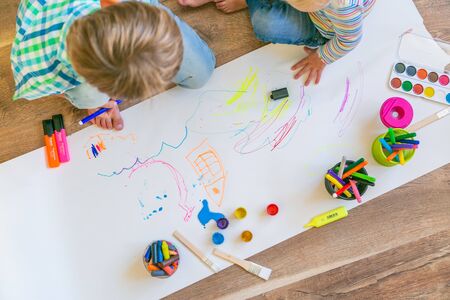 Kids painting with different materials on large canva on the flourの写真素材