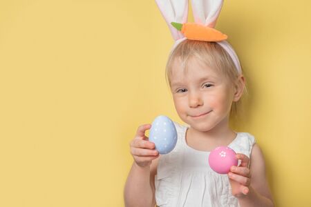 Easter concept - child wearing easter bunny ears and holding eggs