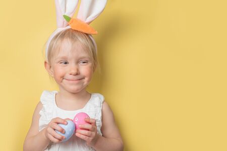 Easter concept - child wearing easter bunny ears and holding eggs