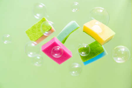Cleaning concept - levitation of dishwashing sponges on green backgroundの写真素材