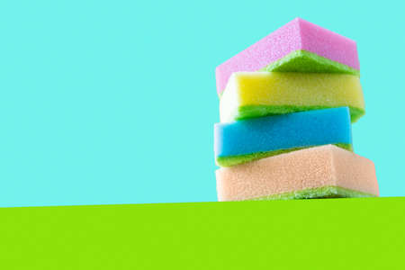 Cleaning concept - colorful dishwashing sponges on bright background