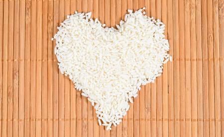 Rice laid out in a heart shape on Bamboo backgroundの写真素材