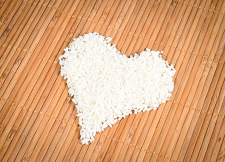 Rice laid out in a heart shape on Bamboo backgroundの写真素材