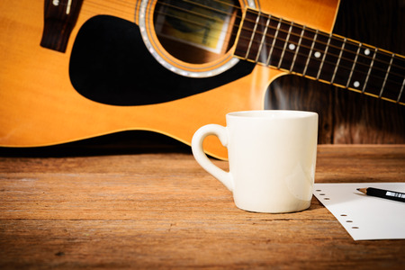 coffee cup and guitar on wooden tableの写真素材