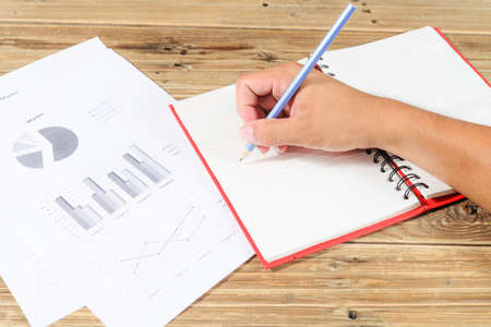 Close-up of male hand holding pencil over notebookの写真素材