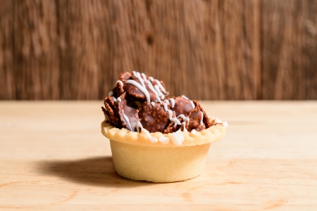Crispy chocolate tarts on wood background