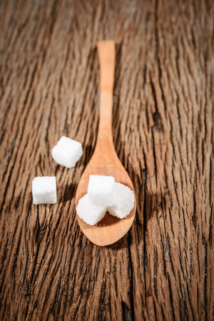 sugar cube  in the spoon on wood backgroundの写真素材