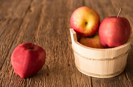 Fresh apple in basket on wooden tableの写真素材