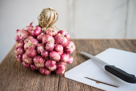 Red onions on a plastic chopping boardの写真素材