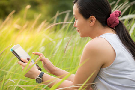 Woman using digital tablet PC in the parkの写真素材