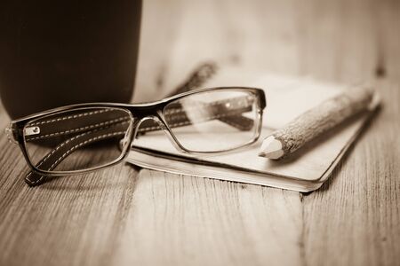 color pencil made of branches with glasses and note book on wood background,Old color styleの写真素材