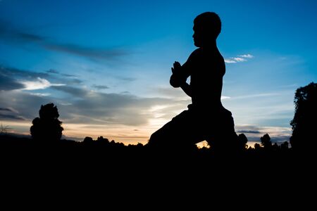 Silhouette of man practicing yoga with beautiful sunsetの写真素材