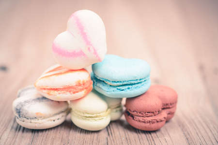 A lot of french colorful macarons on a woody floor in vintage tone styleの写真素材