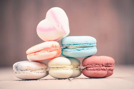 A lot of french colorful macarons on a woody floor in vintage tone styleの写真素材