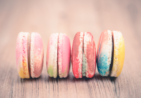 A lot of french colorful macarons on a woody floor in vintage tone styleの写真素材