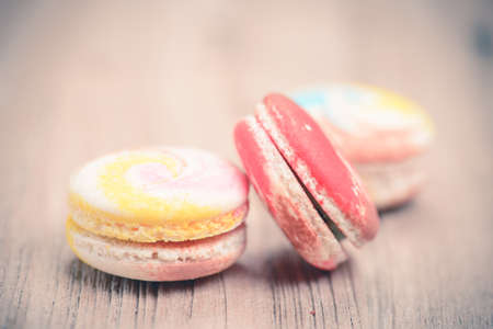 A lot of french colorful macarons on a woody floor in vintage tone styleの写真素材