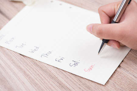 Closeup of woman's hand writing the day on paper