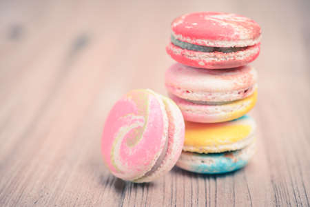A lot of french colorful macarons on a woody floor in vintage tone style
