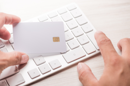 hand holding a white credit card and typing. On-line shopping on the internetの写真素材