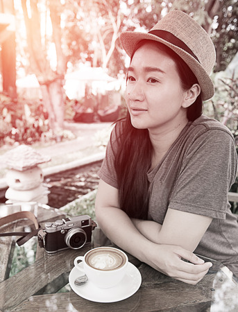 beautiful woman with classic camera and coffee latta art in gaden ; vintage filtered tone styleの写真素材