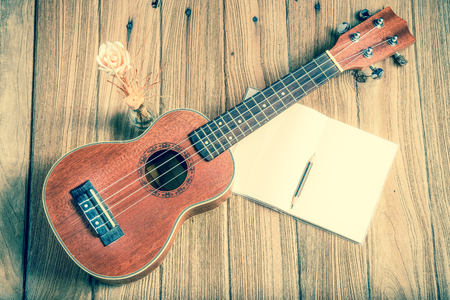 ukulele with notebook on wood background : vintage filtered tone styleの写真素材
