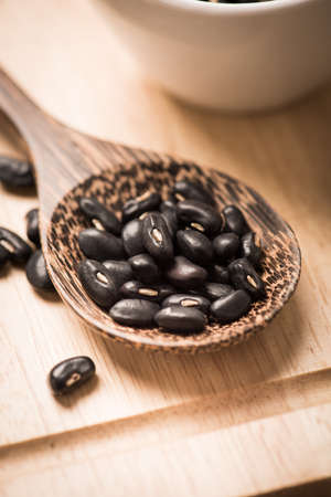 close up of black beans in wooden spoonの写真素材