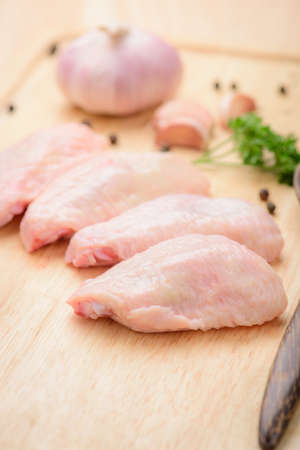 Chicken middle wing with garlic and black pepper on wood blockの写真素材