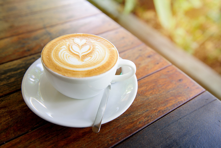 A Cup of hot latte art coffee on wooden tableの写真素材