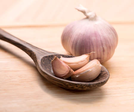 garlic in wooden spoon on a tableの写真素材