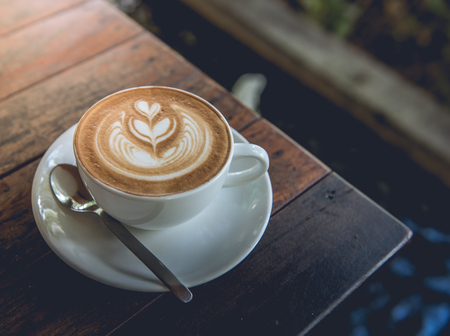 A Cup of hot latte art coffee on wooden table vintage tone styleの写真素材