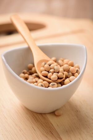 Soybeans in white ceramic bowl on wood blockの写真素材