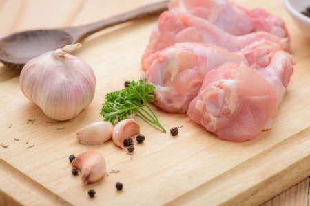 Chicken wings (wingstick) uncooked with garlic  black pepper and parsley on wood blockの写真素材