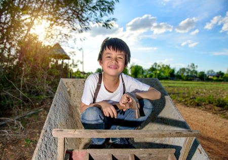 Cute Asian boy playing on a cart with hammer in handの写真素材