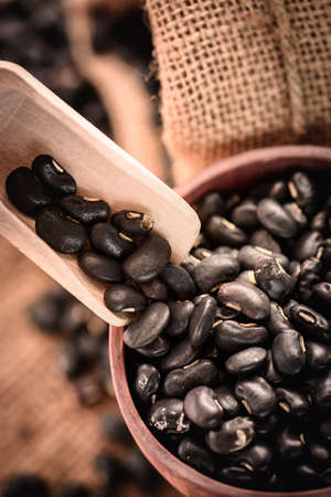 Vigna mungo or black beans in wooden cup with wooden scoop on sack backgroundの写真素材