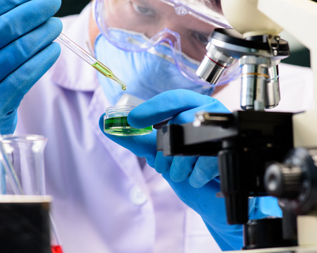 Conical flask in scientist hand with lab glassware background, Laboratory research conceptの写真素材
