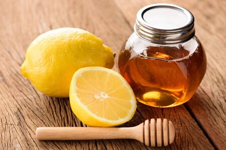 Jars of honey with lemons on wooden tableの写真素材