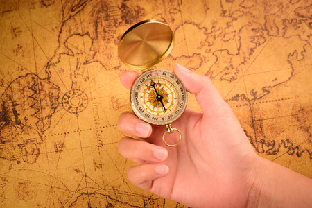 Close up of the hand holding a vintage compass over a vintage mapの写真素材