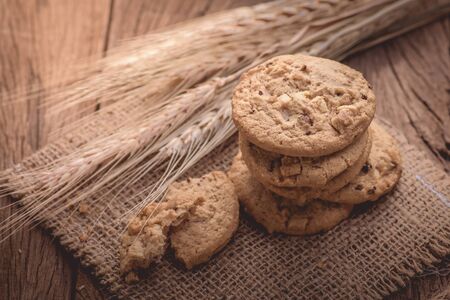 Chocolate cookies on sack background on wooden table. Chocolate chip cookies shot with barley